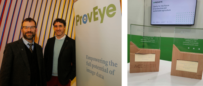 Two men standing and smiling and two award trophies